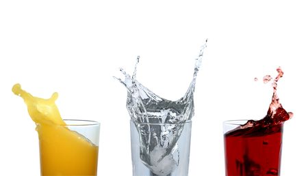 Three glasses with various motley splashing beveragesの写真素材