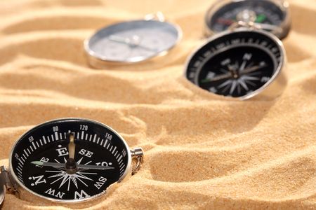 Conceptual background with few compasses lying on sand. Horizontal imageの写真素材