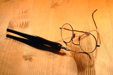 Old spectacles and ink pen lying on nice wooden backgroundの写真素材