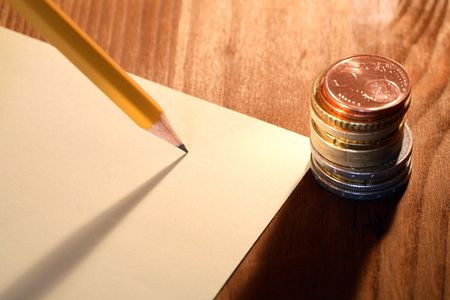 Column of coins near paper and pencil on wooden backgroundの写真素材
