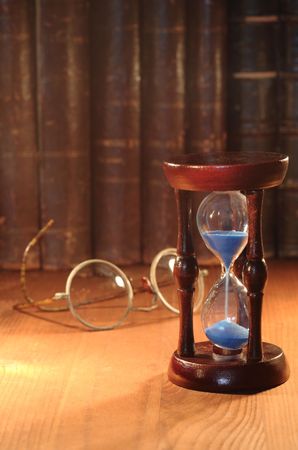 Vintage hourglass on background with old spectacles and booksの写真素材