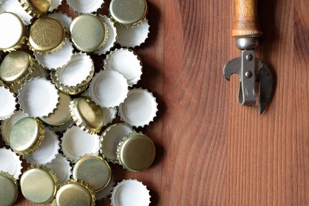 Old opener near lot of bottle caps on wooden backgroundの写真素材