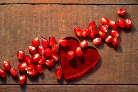 Health concept. Red glass heart and pomegranate seeds on wooden backgroundの写真素材