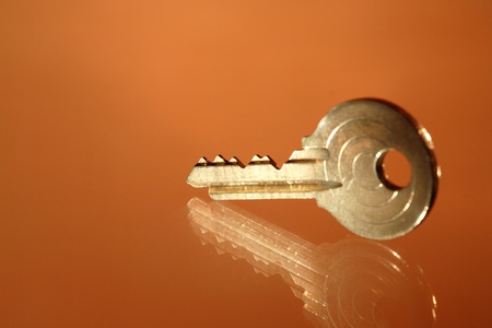 Closeup of yellow metal key lying on glass backgroundの写真素材