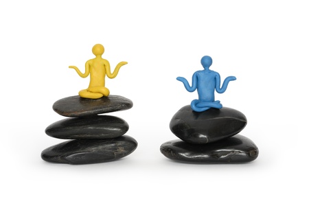 Two color plasticine men meditating in lotus position on black balancing stones. Isolated on white backgroundの写真素材