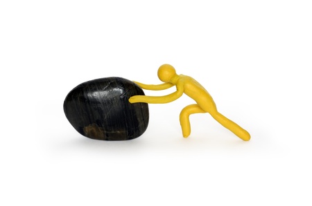 Yellow plasticine man pushing black stone. Isolated on white の写真素材