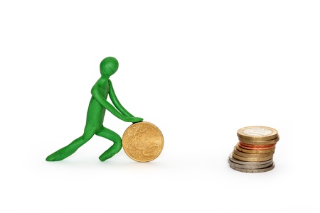 Green plasticine man rolling coin to stack of coins. Isolated on white の写真素材