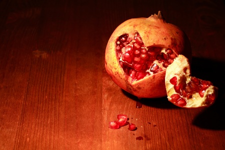 Fresh pomegranate lying on dark wooden background with lighting effectの写真素材