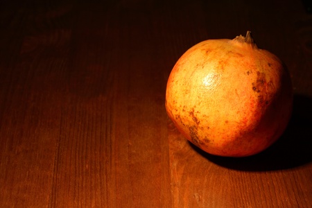 Fresh pomegranate lying on dark wooden background with lighting effectの写真素材