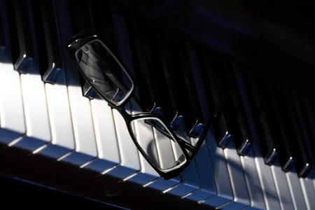 Closeup of black eyeglasses lying on piano keys. Black copy spase for your textの写真素材