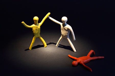 Three color plasticine men as boxers and referee on dark background. One boxer is lying and other is...