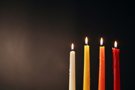 Set of four colored lighting candles on dark backgroundの写真素材