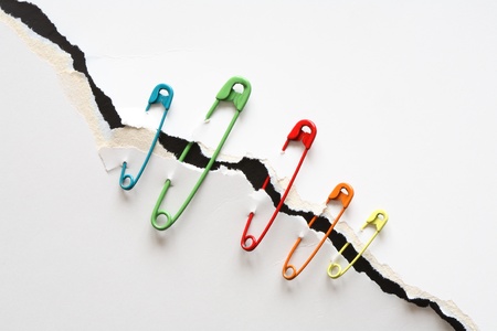Set of color safety pins attached to disrupt white paper 