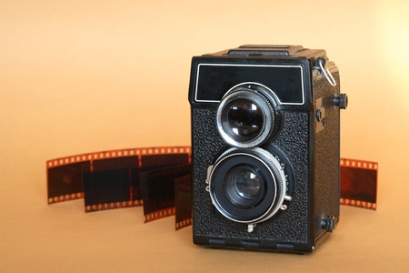 Vintage twin lens camera near film isolated on nice yellow background