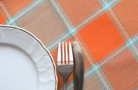 Fork and knife lying near plate on checkered tableclothの写真素材
