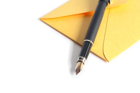 Closeup of fountain pen lying on yellow envelope on white backgroundの写真素材