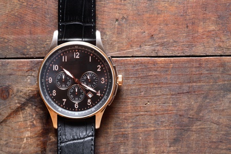Closeup of modern wristwatch lying on wooden surface