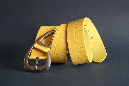Nice yellow belt with metal buckle on dark backgroundの写真素材