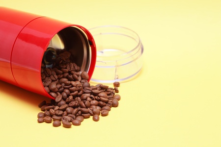 Lot of coffee beans near open modern red grinder on yellow backgroundの写真素材