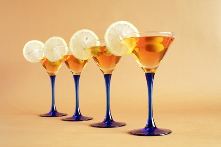 Four martini glasses with lemon and olives standing in a rowの写真素材