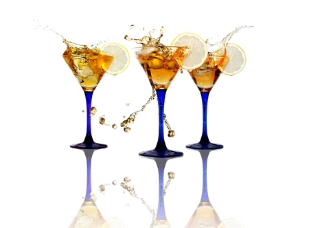 Three wineglasses with splashing beverage and lemon on white backgroundの写真素材