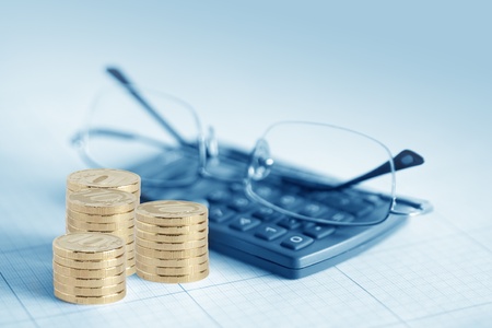 Few coin columns near calculator and spectacles on gray backgroundの写真素材