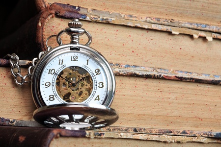 Vintage pocket watch with open lid on background with old booksの写真素材