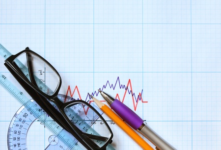 Closeup of spectacles and office tools on graph paper with diagram