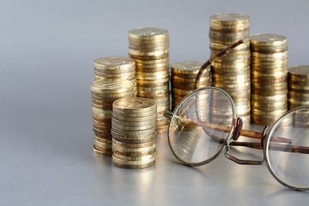Closeup of coins and old spectacles on gray background