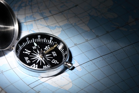 Navigation concept. Open compass lying on map under beam of light