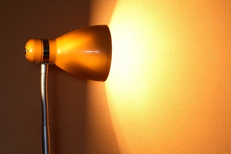 Modern luminous desk lamp with beam of light near yellow wall. Good background for textの写真素材