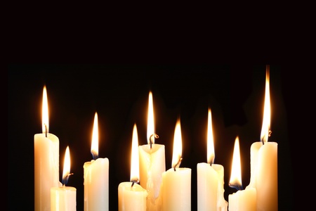 Nine ordinary lighting candles in a row on black backgroundの写真素材