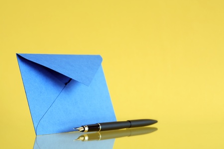 Blue envelope near fountain pen on yellow backgroundの写真素材