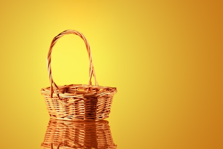 Empty wicker basket on nice yellow background with reflectionの写真素材