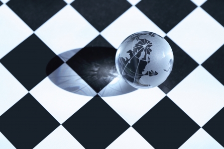 Chess concept. Transparent glass globe lying on chessboardの写真素材