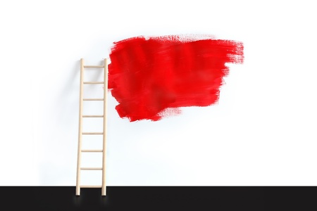 Painting concept. Wooden ladder near white wall with big red spot of paint for textの写真素材