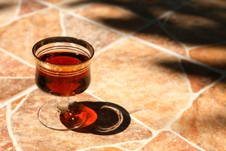 Goblet of port wine or cognac on stone surfase under sun beamの写真素材