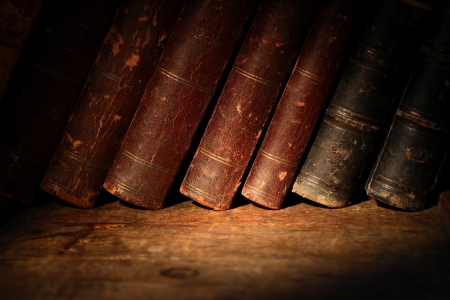 Stack of old books in a row on wooden surfaceの写真素材