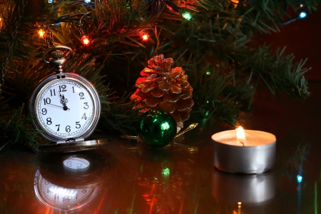 Vintage pocket watch near Christmas tree and lighting candleの写真素材