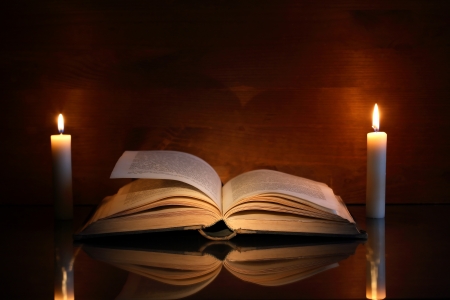 Vintage still life with open old book near two lighting candlesの写真素材