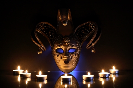 Beautiful classical venetian mask near lighting candles on dark backgroundの写真素材