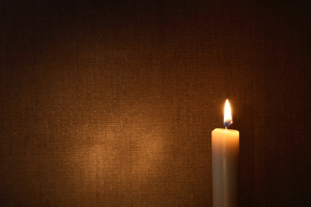 Lighting candle against canvas background with free space for textの写真素材