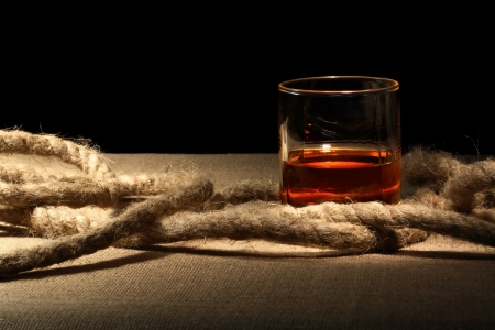 Closeup of glass of rum near rope on canvas surfaceの写真素材