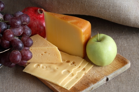 Still life with few sorts of cheese and fruits on wooden hardboardの写真素材