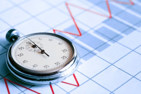 Business concept. Closeup of stopwatch on paper background with business chartの写真素材