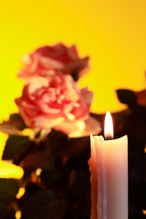Closeup of lighting candle on yellow background with flowersの写真素材