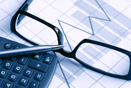 Business concept. Calculator and stectacles on paper background with chartの写真素材