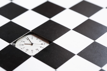 Time concept. Clock inside hole in black and white checkered surfaceの写真素材