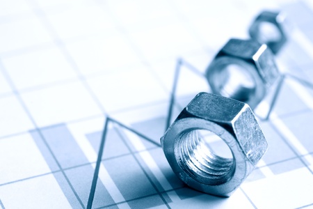 Few screw nuts in a row on paper background with business chart