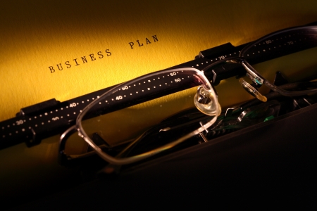 Spectacles lying on typewriter. BUSINESS PLAN inscription on paper sheetの写真素材